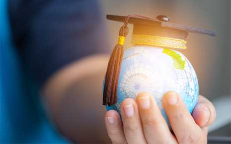 Hand holding a globe with graduation cap